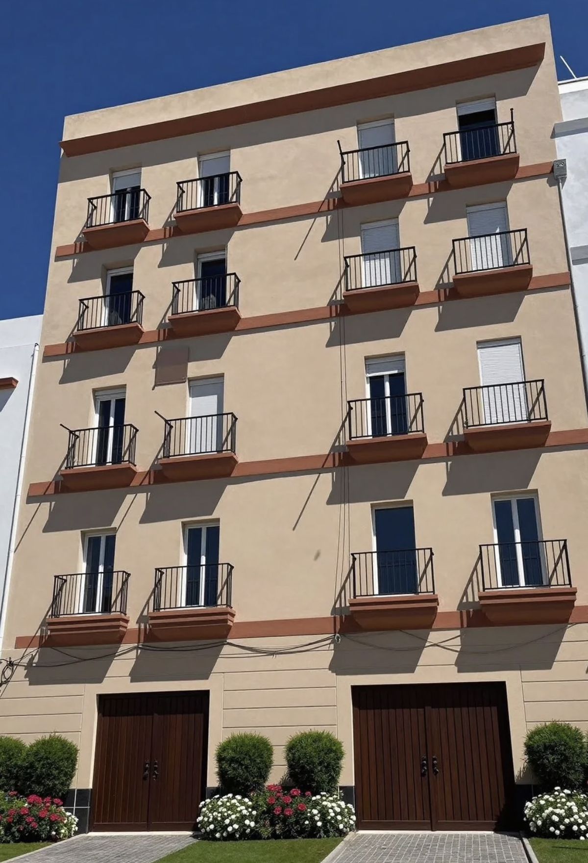 Kamienica po renowacji — odnowiony tynk, nowe bramy garażowe, kwiaty i zieleń