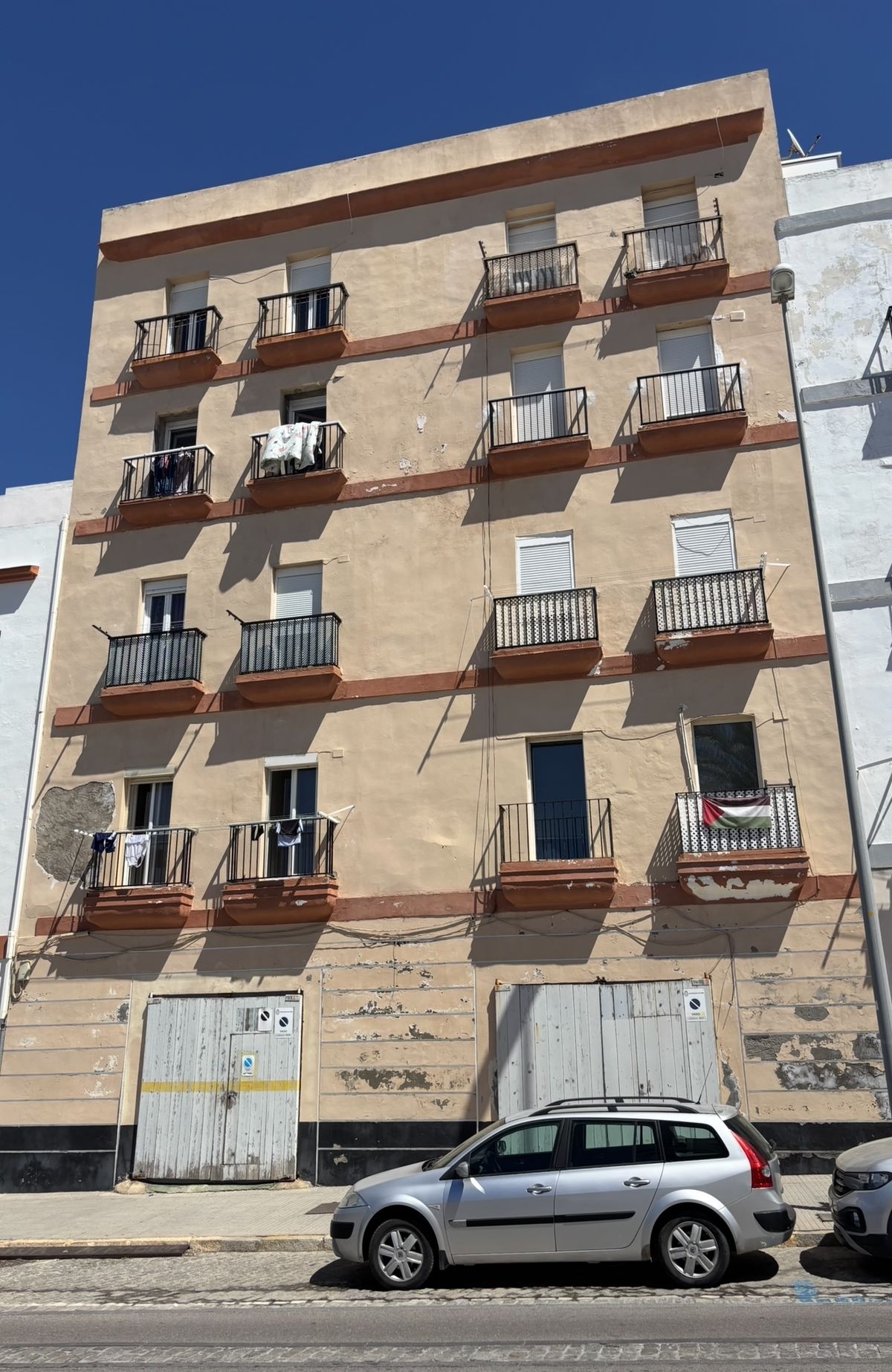 Kamienica przed renowacją — odpadający tynk, zniszczona elewacja, stare bramy